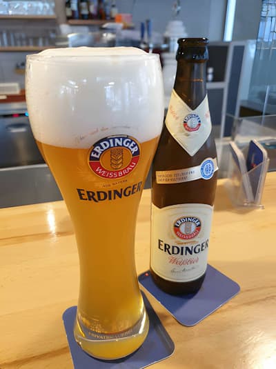 Frisch eingeschenktes Erdinger Weissbier mit Flasche auf dem Holztresen der Huefyse-Bar
