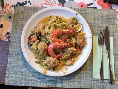 Teller mit frisch zubereiteter Paella mit Crevetten und Muscheln in der Huefyse-Bar